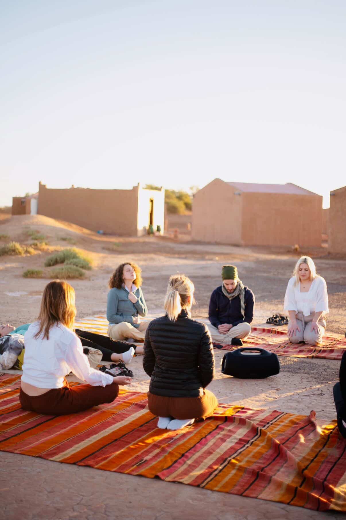 Cercle de méditation au lever du soleil devant le campement