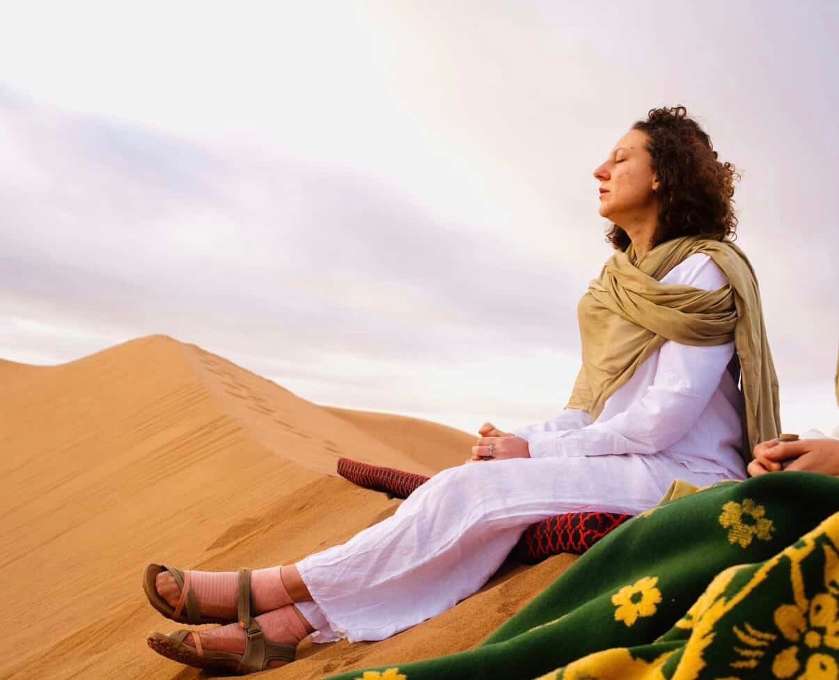 Jade en méditation au sommet d'une dune, dans le désert marocain