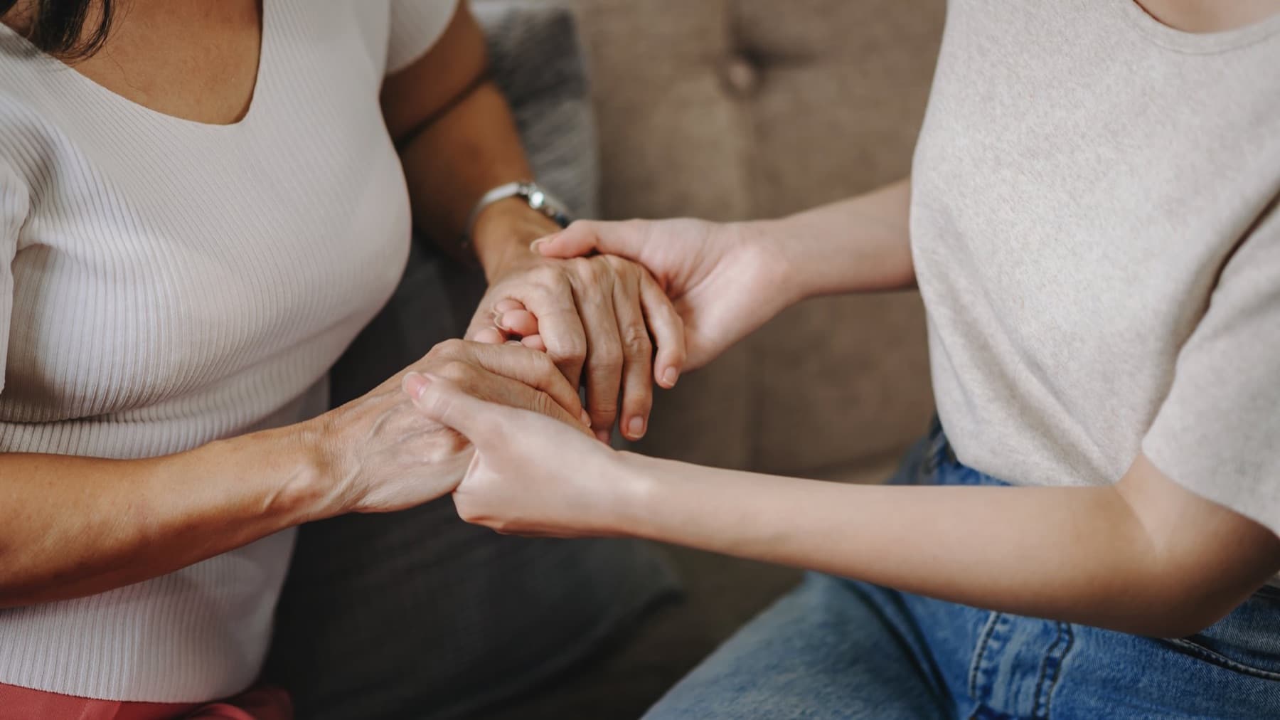 Deux femmes assises côte à côte, se tenant les mains
