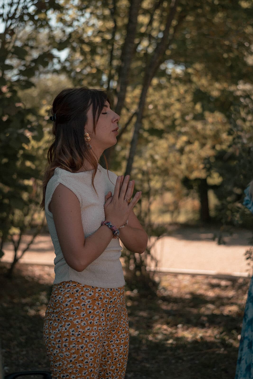 Jade Rouget, les mains sur le cœur, en méditation sous les arbres